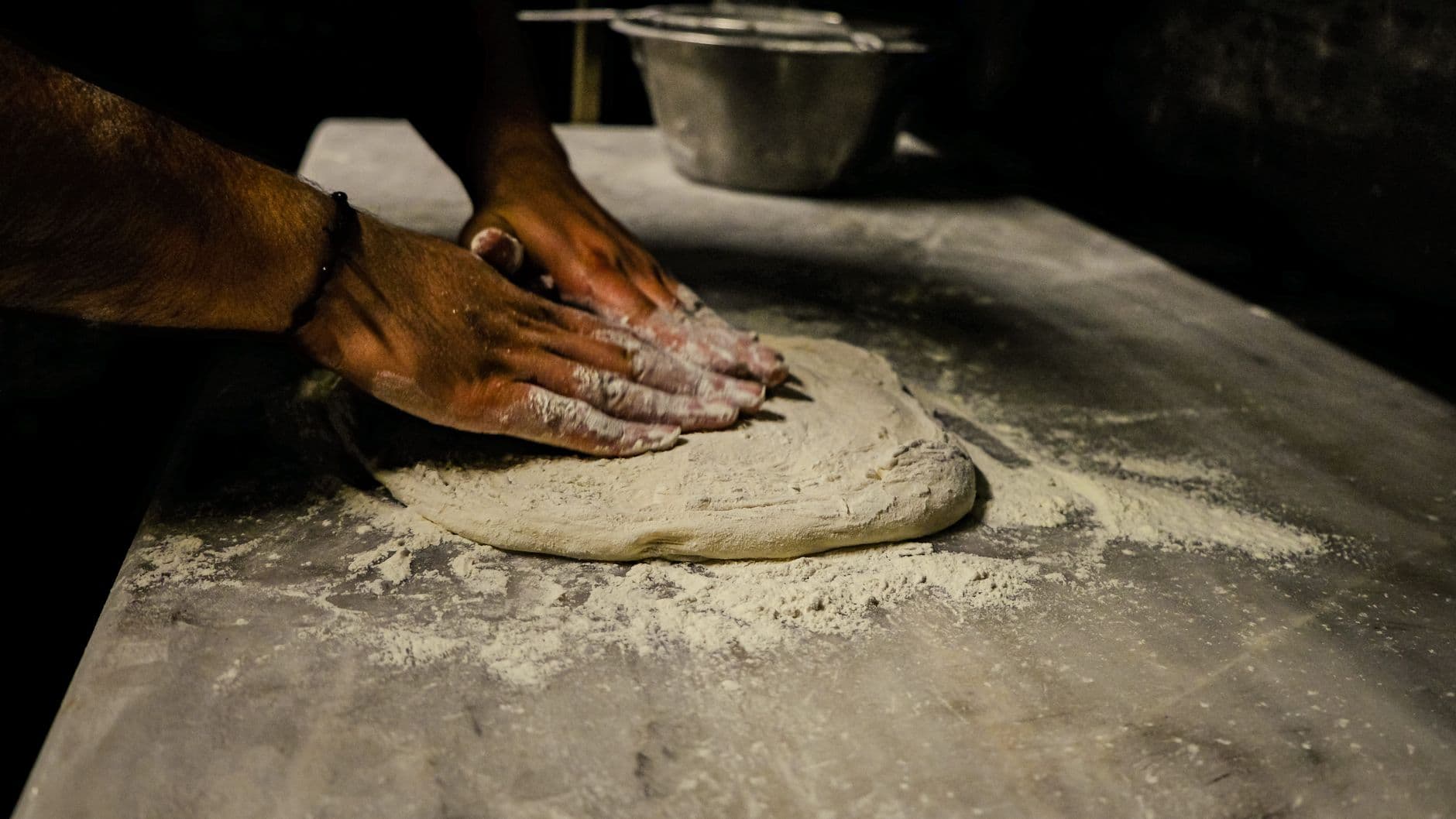 Hands working dough at a wood counter.